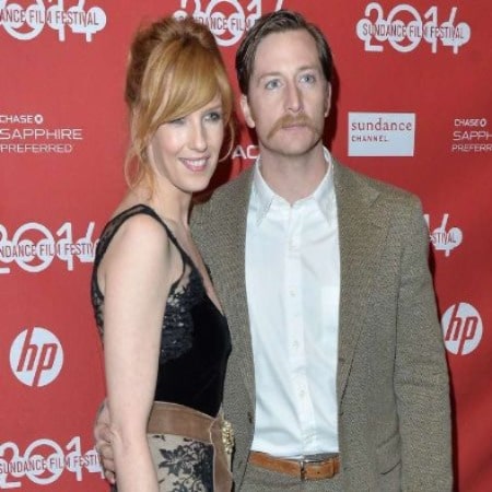 Kelly Reilly has brown hair and her husband Kyle Baugher has brown hair and maustache.